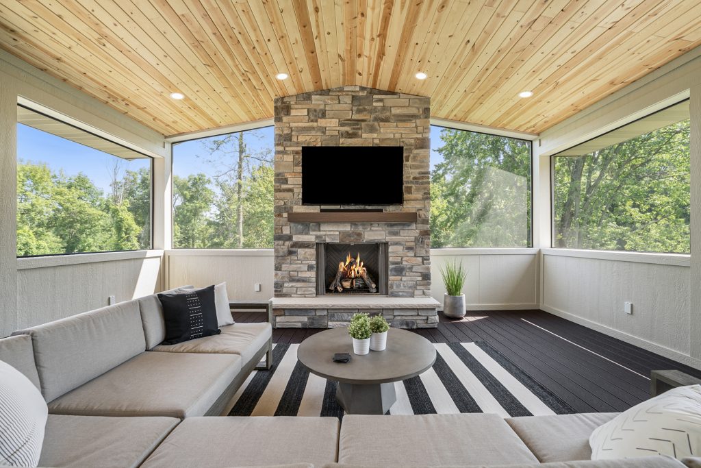 covered and screened in deck with a fireplace and outdoor kitchen
